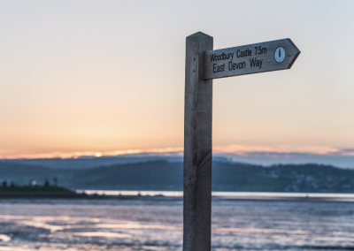 A sign post with Exmouth Estuary body of water in the background