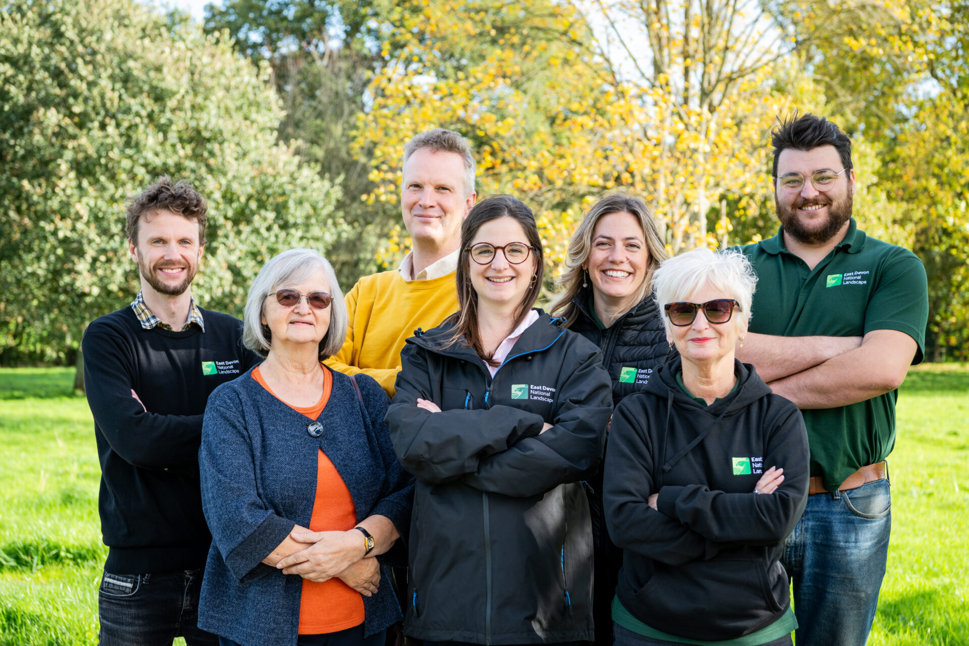 a team photo of people stood outside with autumn colour